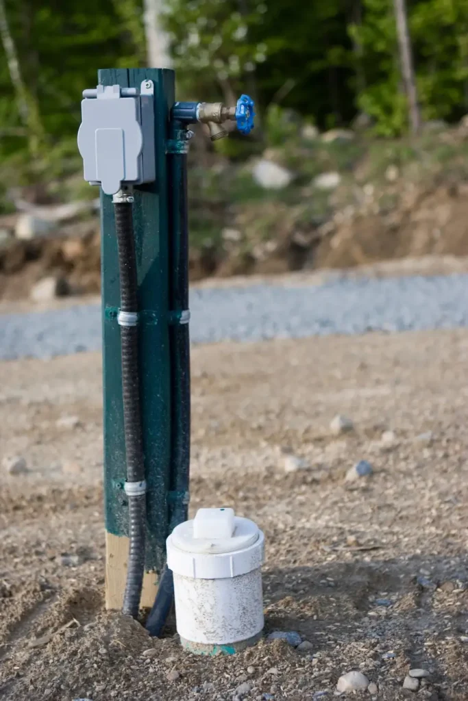 A campsite pedestal with electrical box, water spigot and capped sewer riser