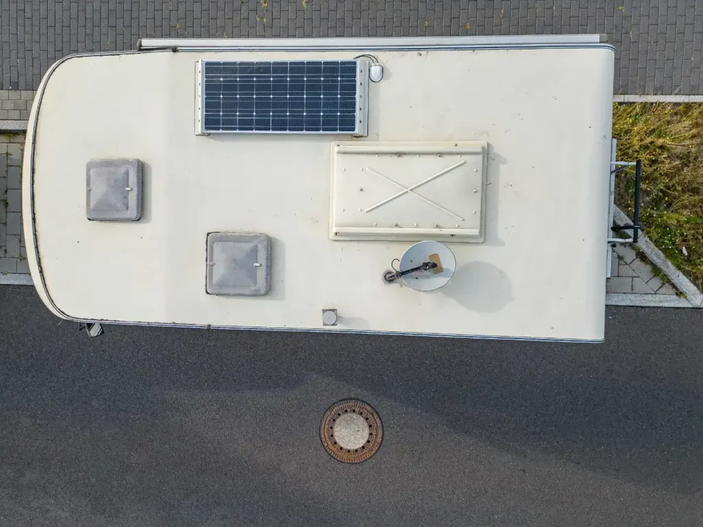Motorhome roof seen from above with a solar panel, two roof vents and a satellite dome