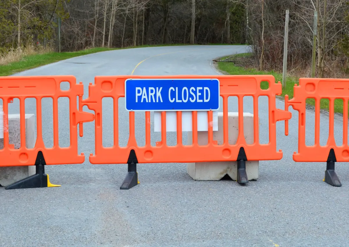 Barricade and closure sign blocking the entrance road to a national park