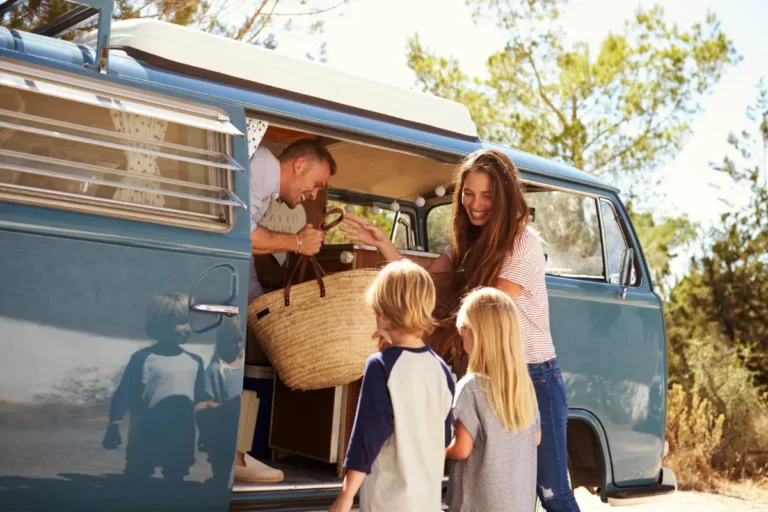 Family packing camping gear into a camper van before a road trip