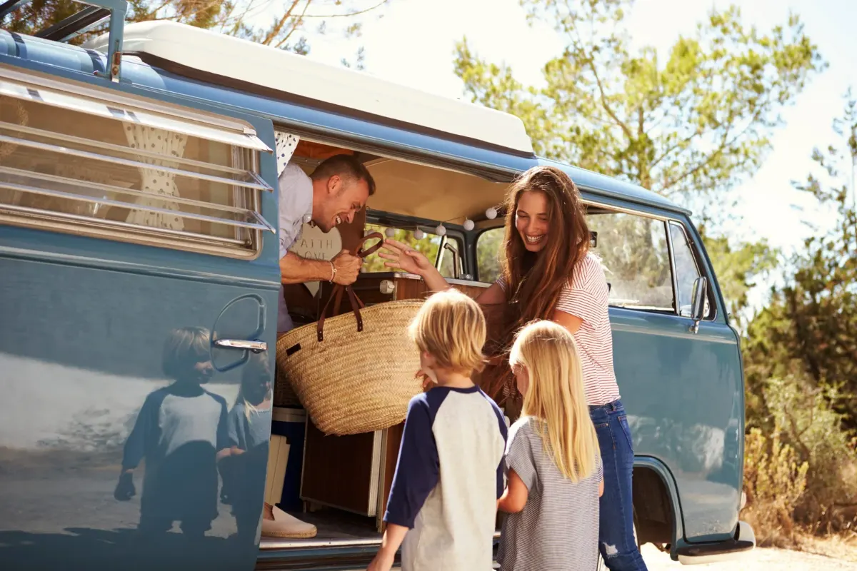 Family packing camping gear into a camper van before a road trip