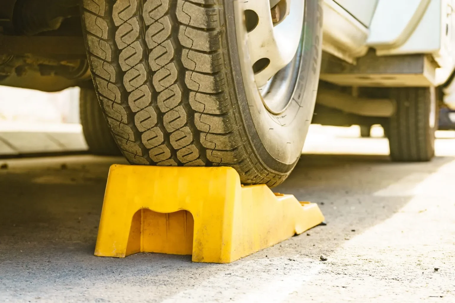 Yellow plastic levelling block under an RV tire on a campsite pad