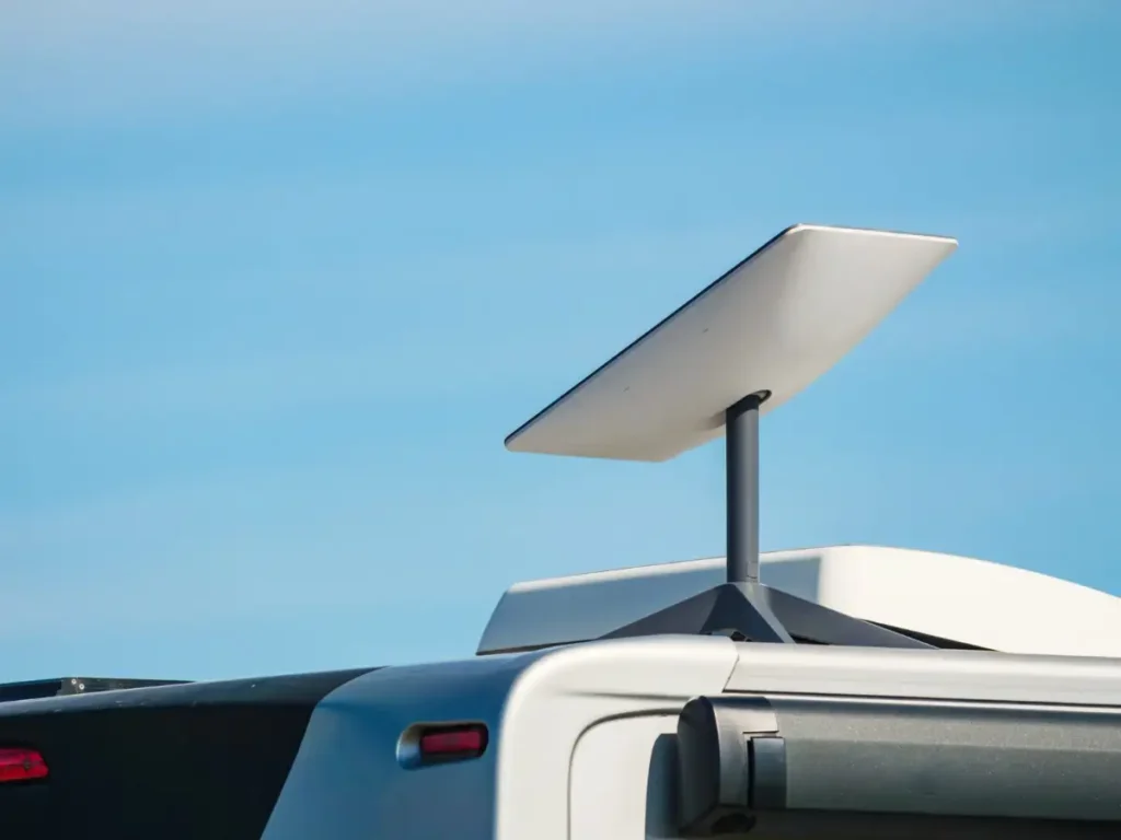 A flat satellite internet dish mounted on the roof of an RV under clear sky