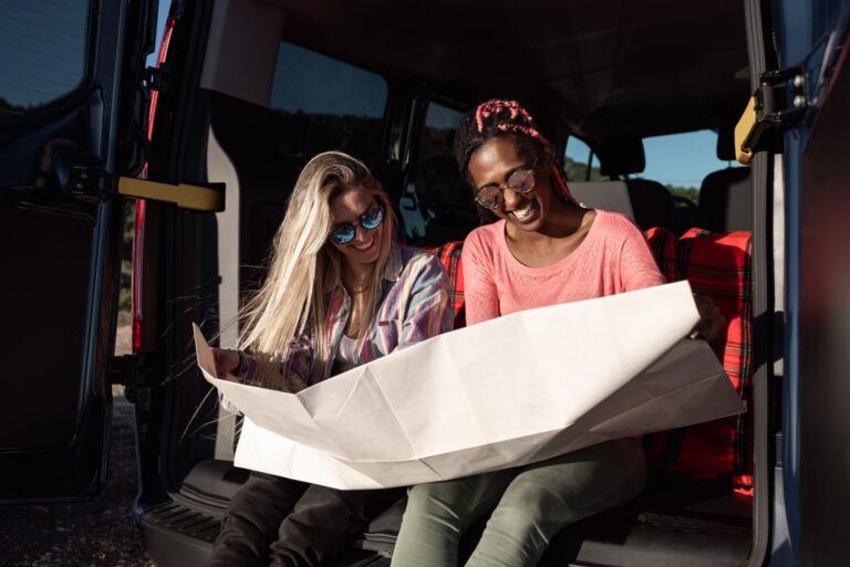 Two travelers reviewing a paper map inside a campervan