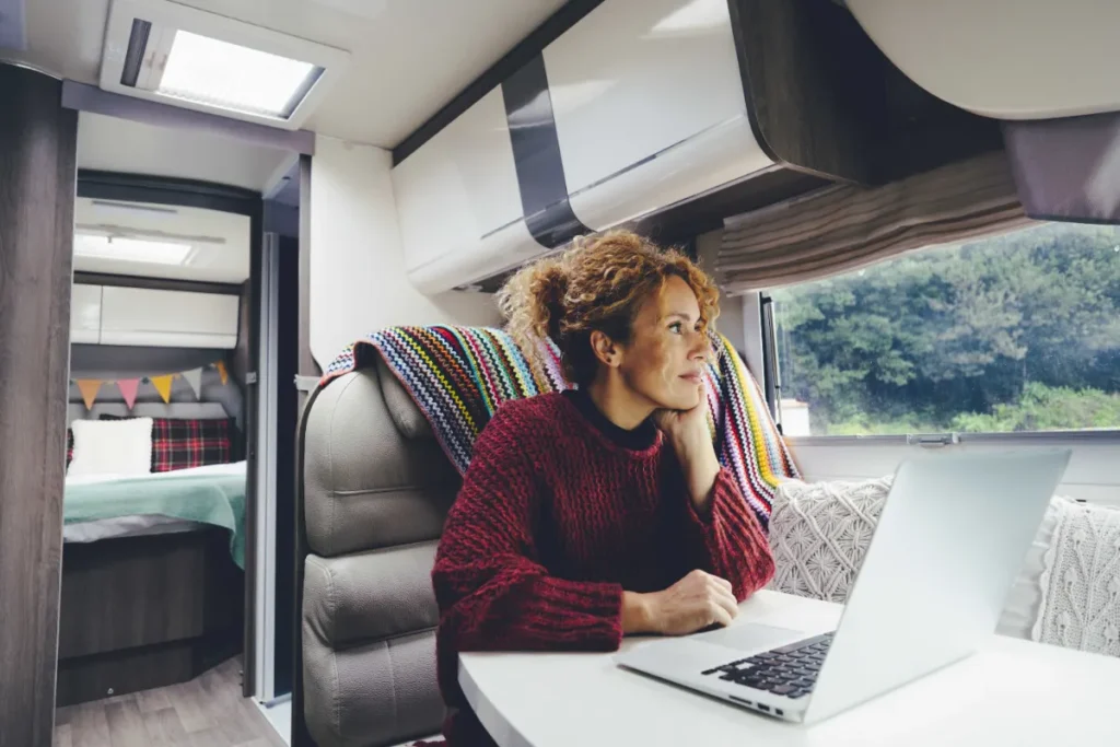 Traveller working on a laptop at the dinette table inside a motorhome
